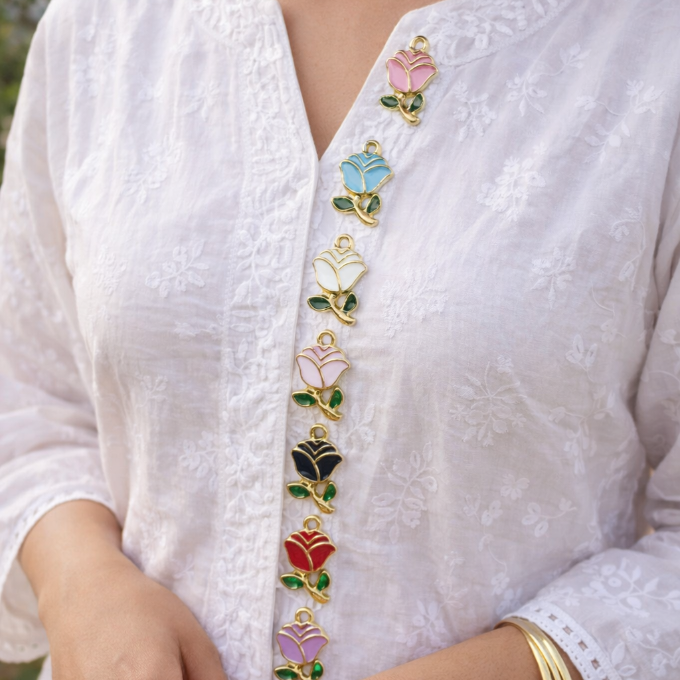 White embroidered garment with colorful floral buttons on a blurred natural background